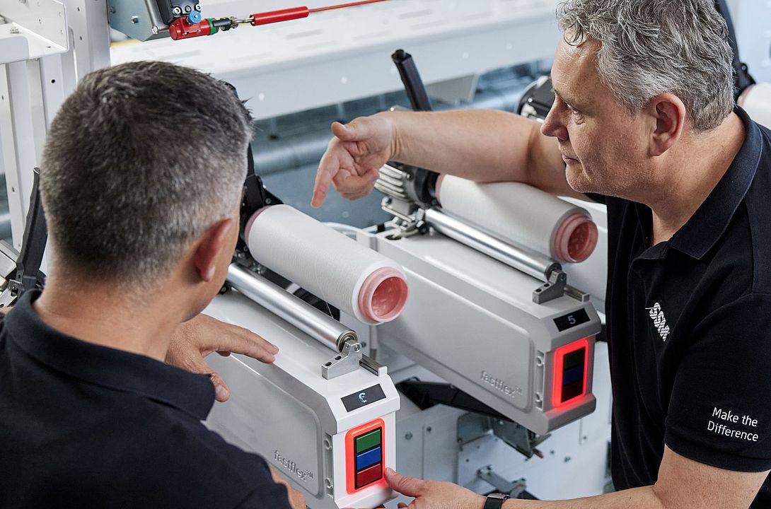 SSM textile technologist explaining the details of an assembly winding machine to a customer during a training session.