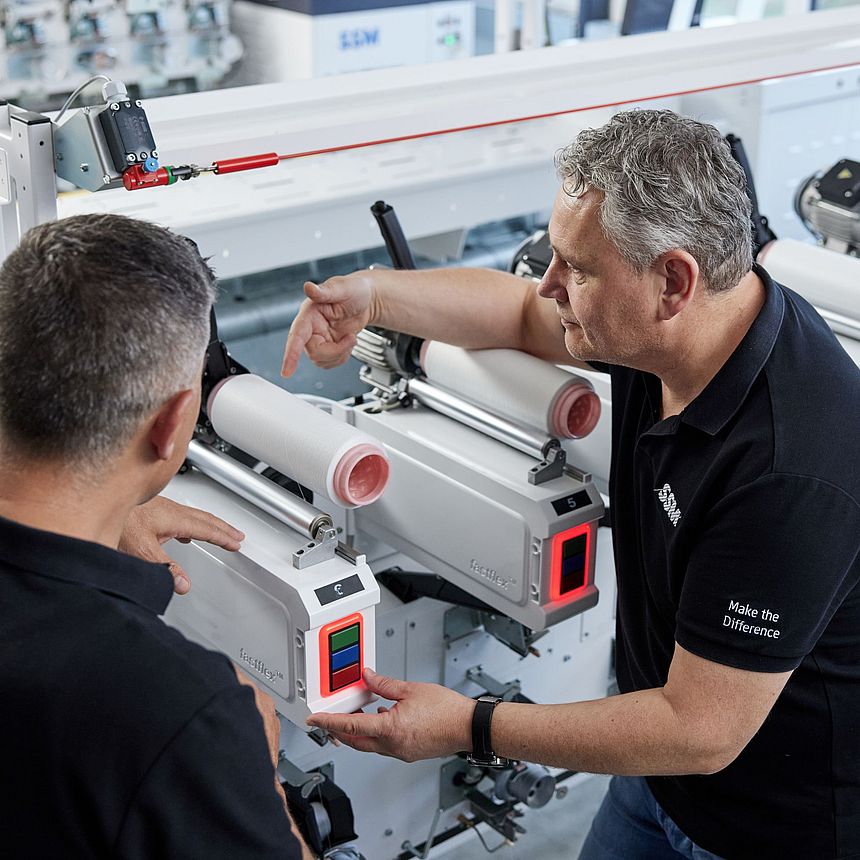 SSM textile technologist explaining the details of an assembly winding machine to a customer during a training session.