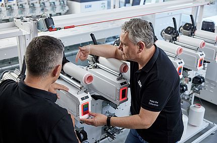 SSM textile technologist explaining the details of an assembly winding machine to a customer during a training session.
