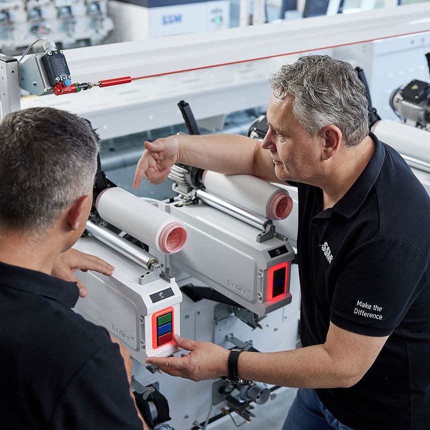 SSM textile technologist explaining the details of an assembly winding machine to a customer during a training session.