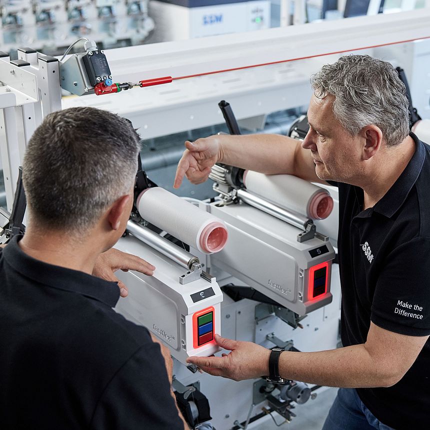 SSM textile technologist explaining the details of an assembly winding machine to a customer during a training session.